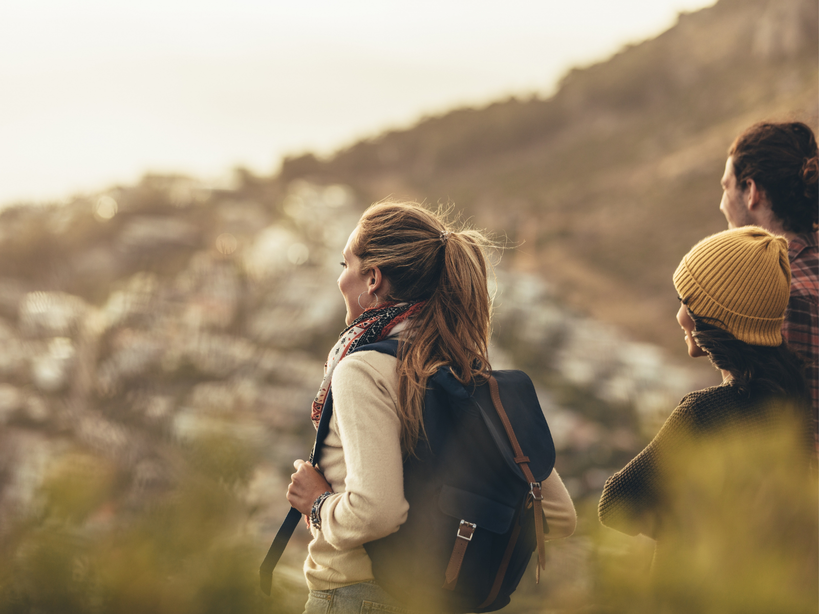 Eine 3er-Gruppe blickt gegen den Horizont und genießt die Aussicht beim Wandern.