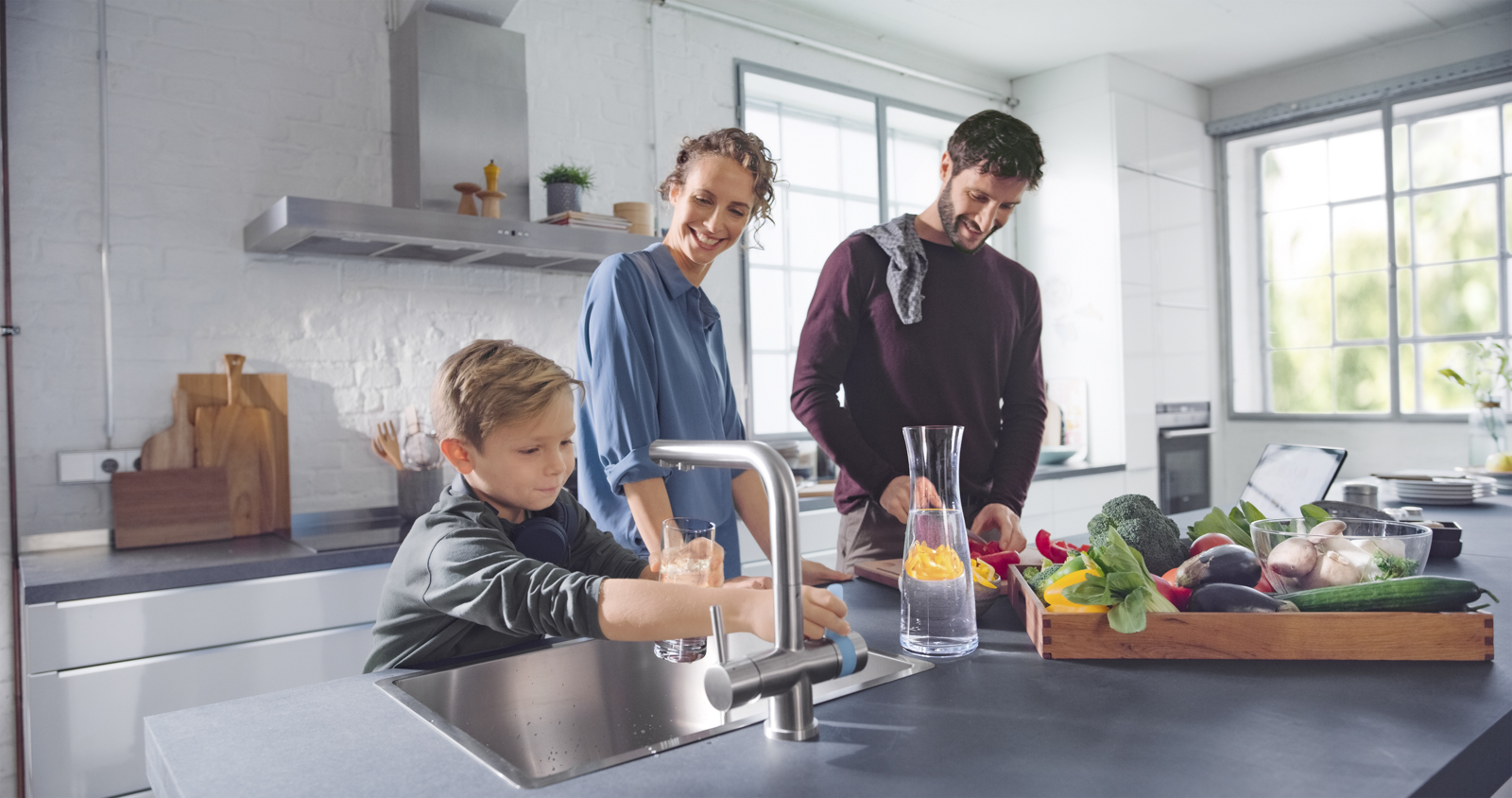 Junge füllt am BRITA 3 Wege Küchenarmatur Glas auf Junge füllt am BRITA 3 Wege Küchenarmatur Glas auf