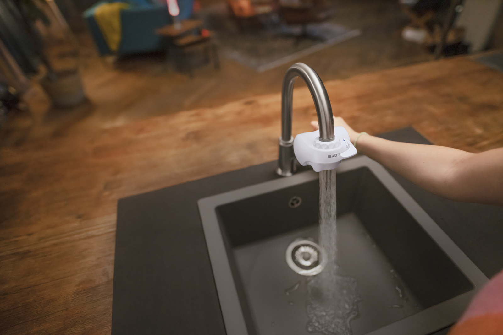 Frau schaltet am BRITA ON TAP V die Brausefunktion an Eine Frau schaltet am BRITA ON TAP V die Brausefunktion an