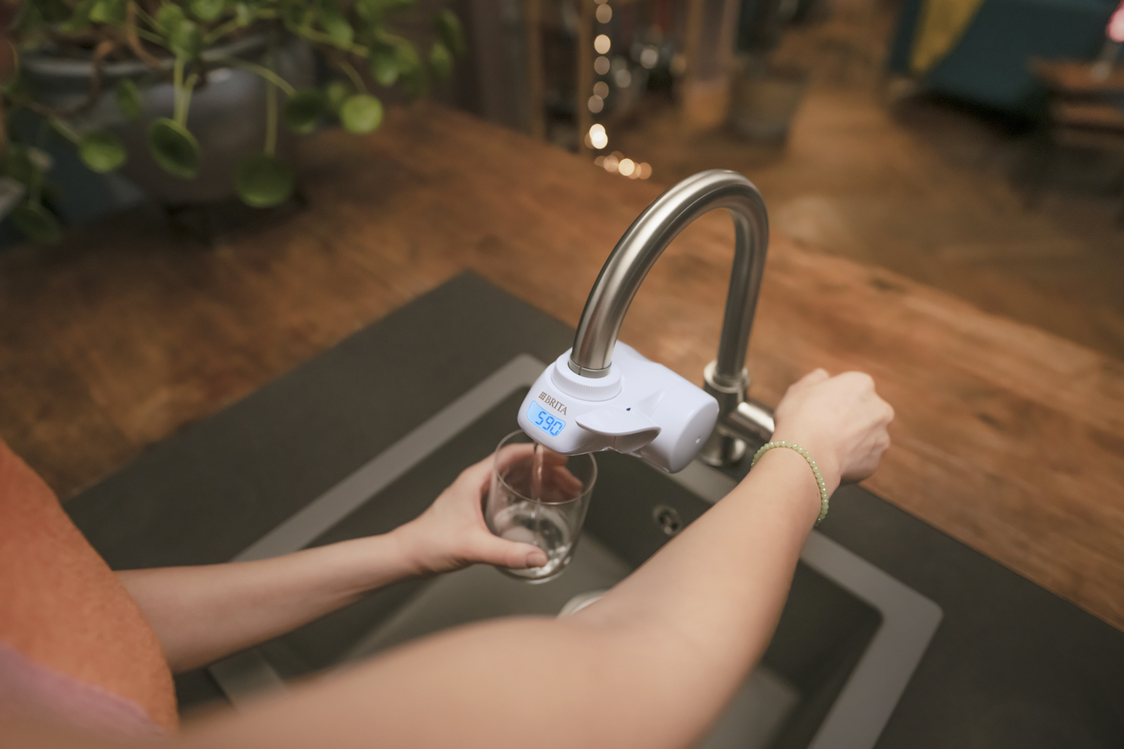 Eine Frau gießt mit dem BRITA ON TAP Pro V-MF Wasser in ein Glas ein