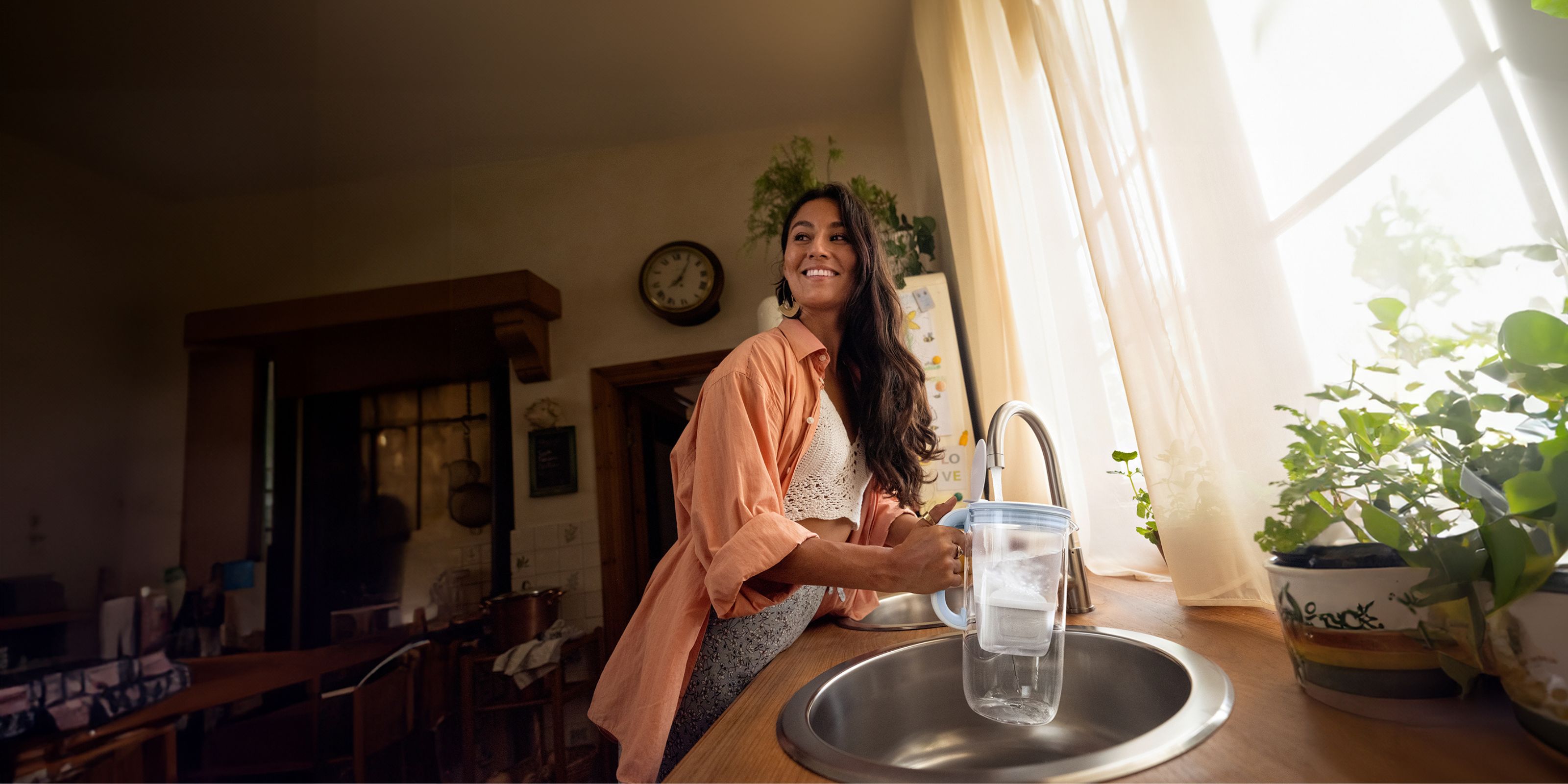 Junge Frau füllt Wasser in Tischwasserfilter Glas
