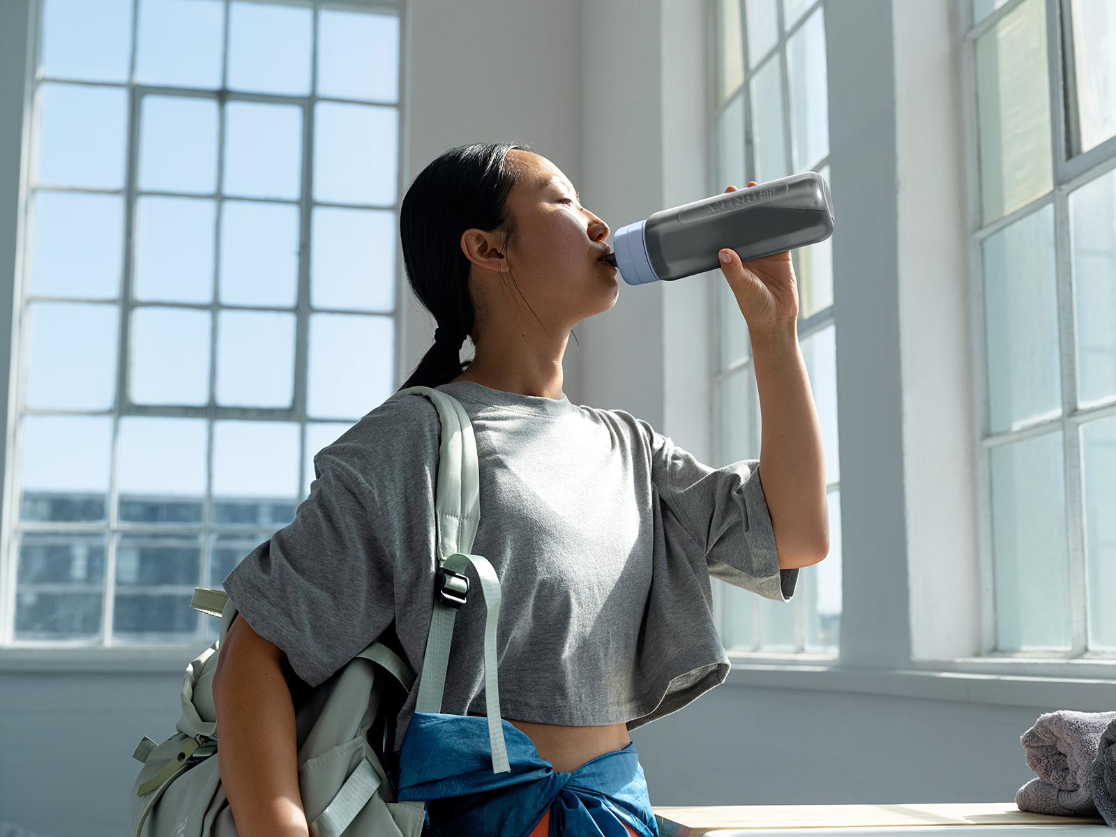 Frau in Sportkleidung trinkt Wasser aus einer BRITA Flasche