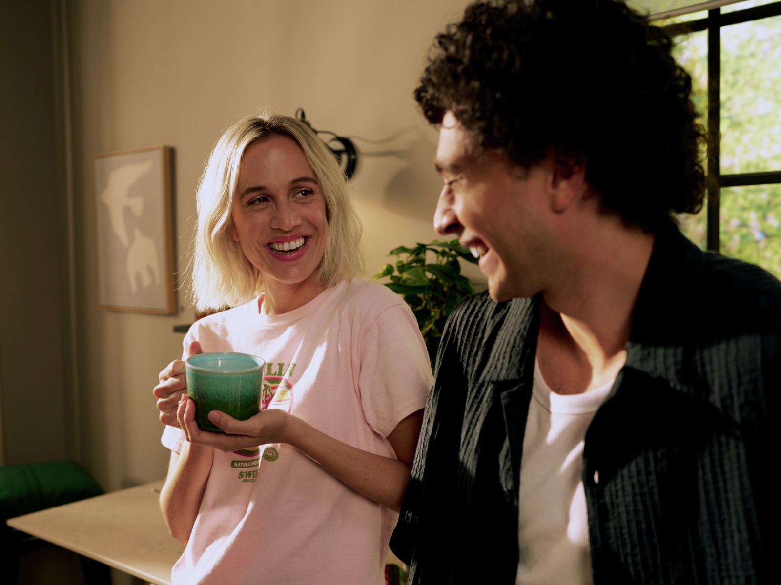 Eine Frau mit einer Kaffeetasse in der Hand unterhält sich mit einem Mann