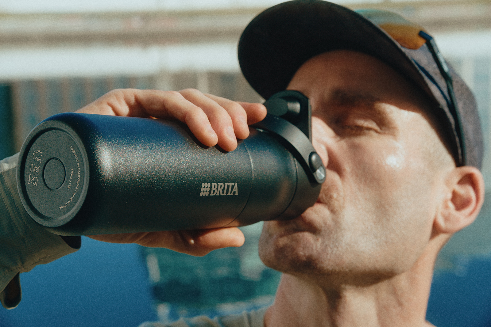 Nahaufnahme eines sportlichen Läufers, der aus einer schwarzen BRITA‑Trinkflasche trinkt