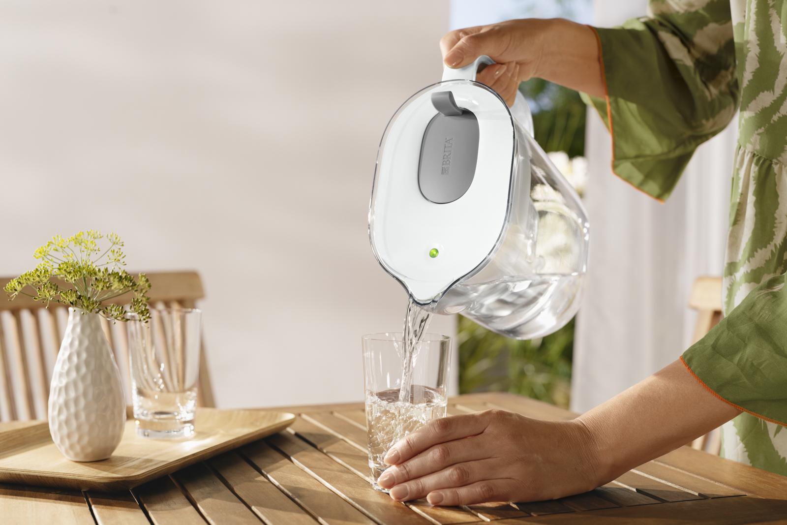 Wasser wird aus BRITA Style XL eingeschenkt. Eine Frau gießt draußen ein Glas Wasser aus dem BRITA Style XL in Grau ein.