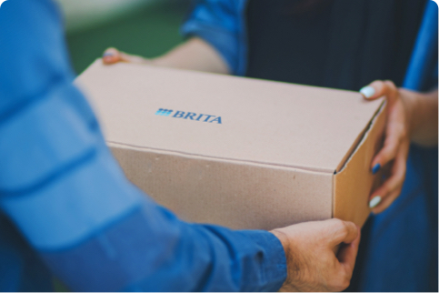 Übergabe eines Pakets mit BRITA-Logo auf der Oberseite Übergabe eines Pakets mit BRITA-Logo auf der Oberseite