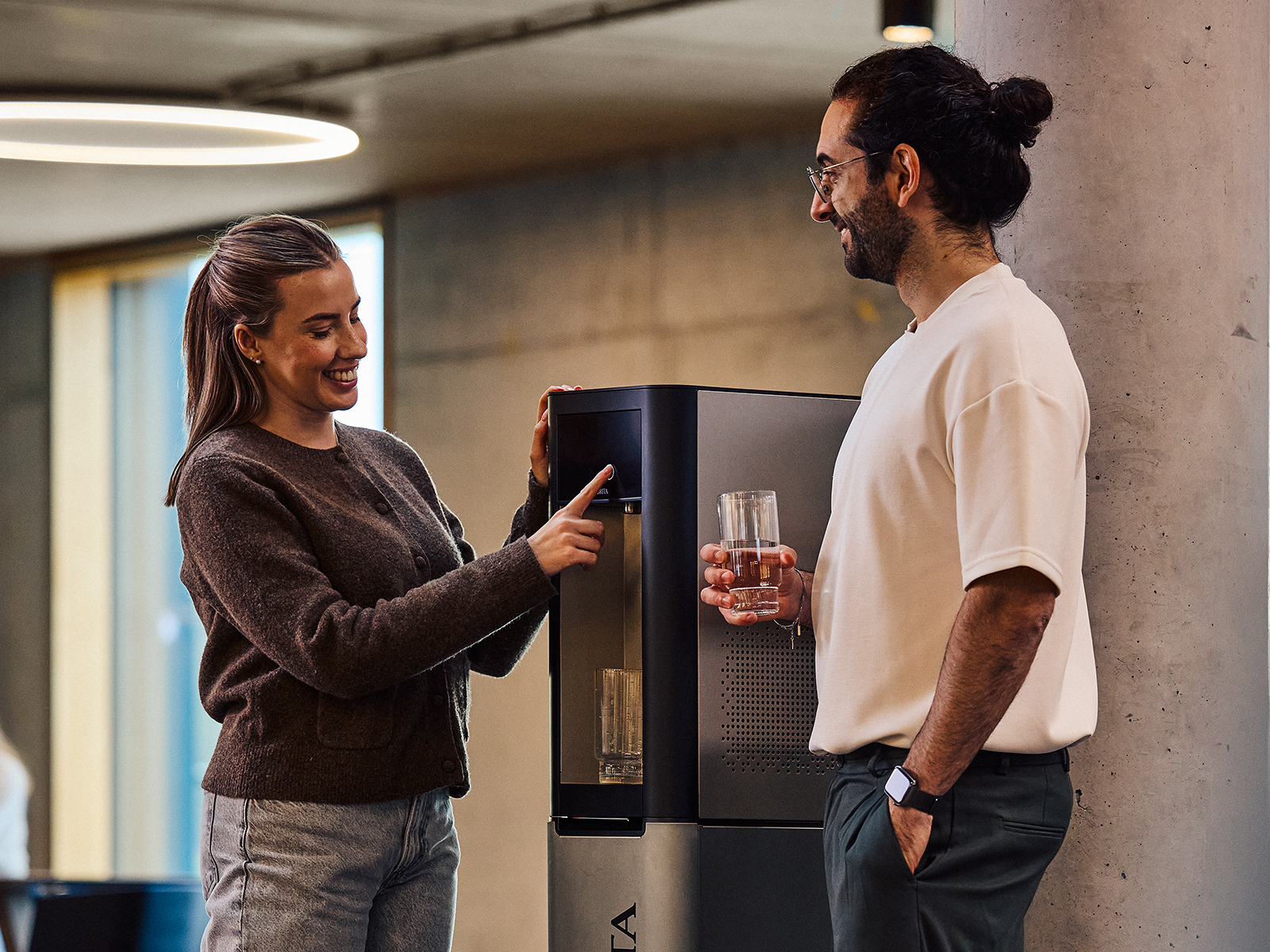 Zwei Personen im Büro füllen Gläser mit Wasser an einem BRITA Wasserspender