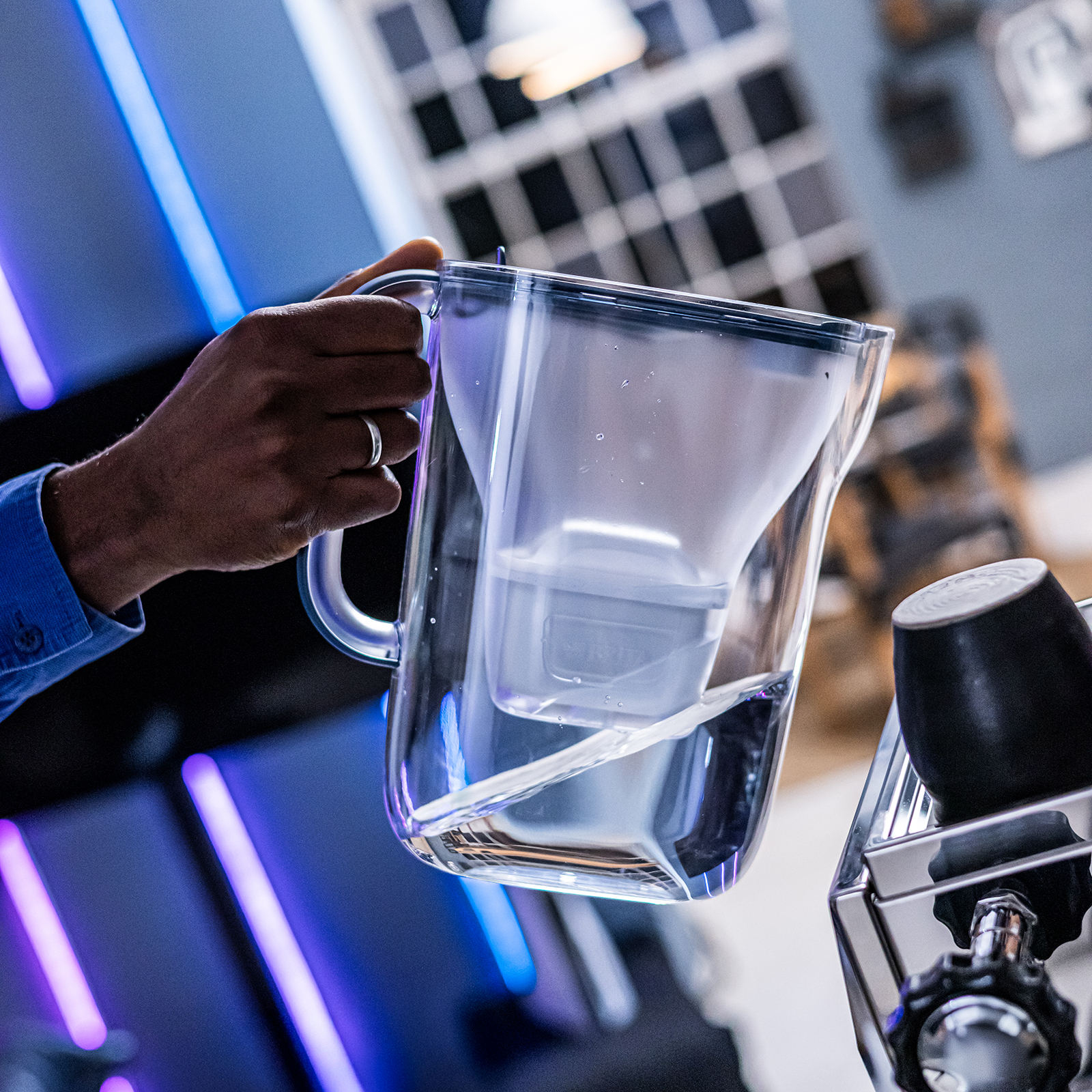 Eine Person gießt Wasser aus dem Style Essential in die Kaffeemaschine.