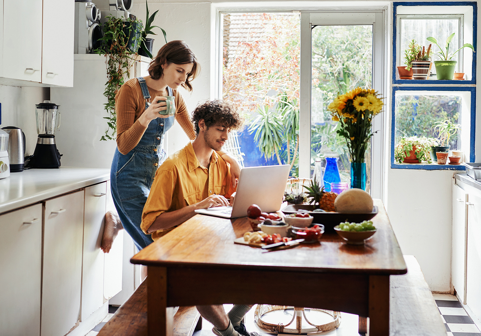 Ein junges Paar in einer Küche schaut gemeinsam auf einen Laptop