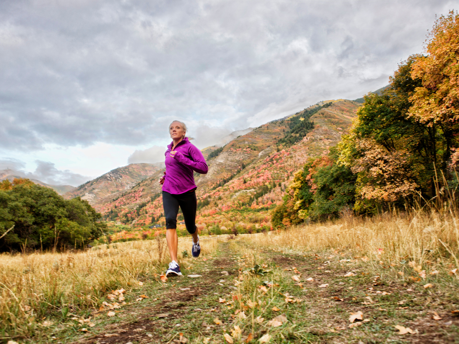 Frau läuft auf einem Trail in Herbstfarben und atmet die kühle Luft ein