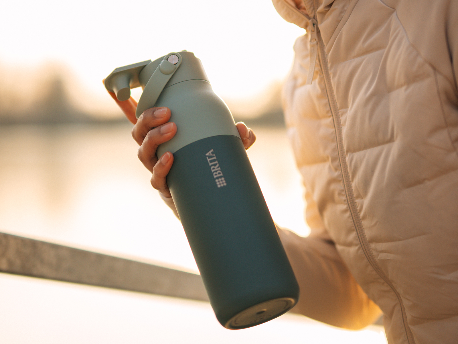 Frau hält eine grüne BRITA LARQ Essential Flasche beim Joggen.
