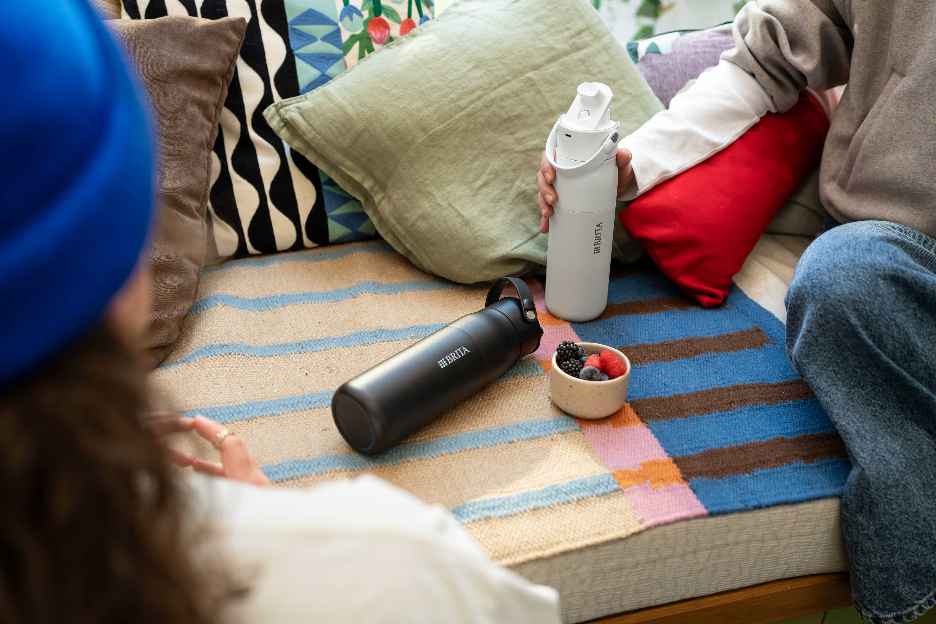 Eine schwarze und weiße BRITA LARQ iQ Trinkflasche auf einem bunten Teppich.