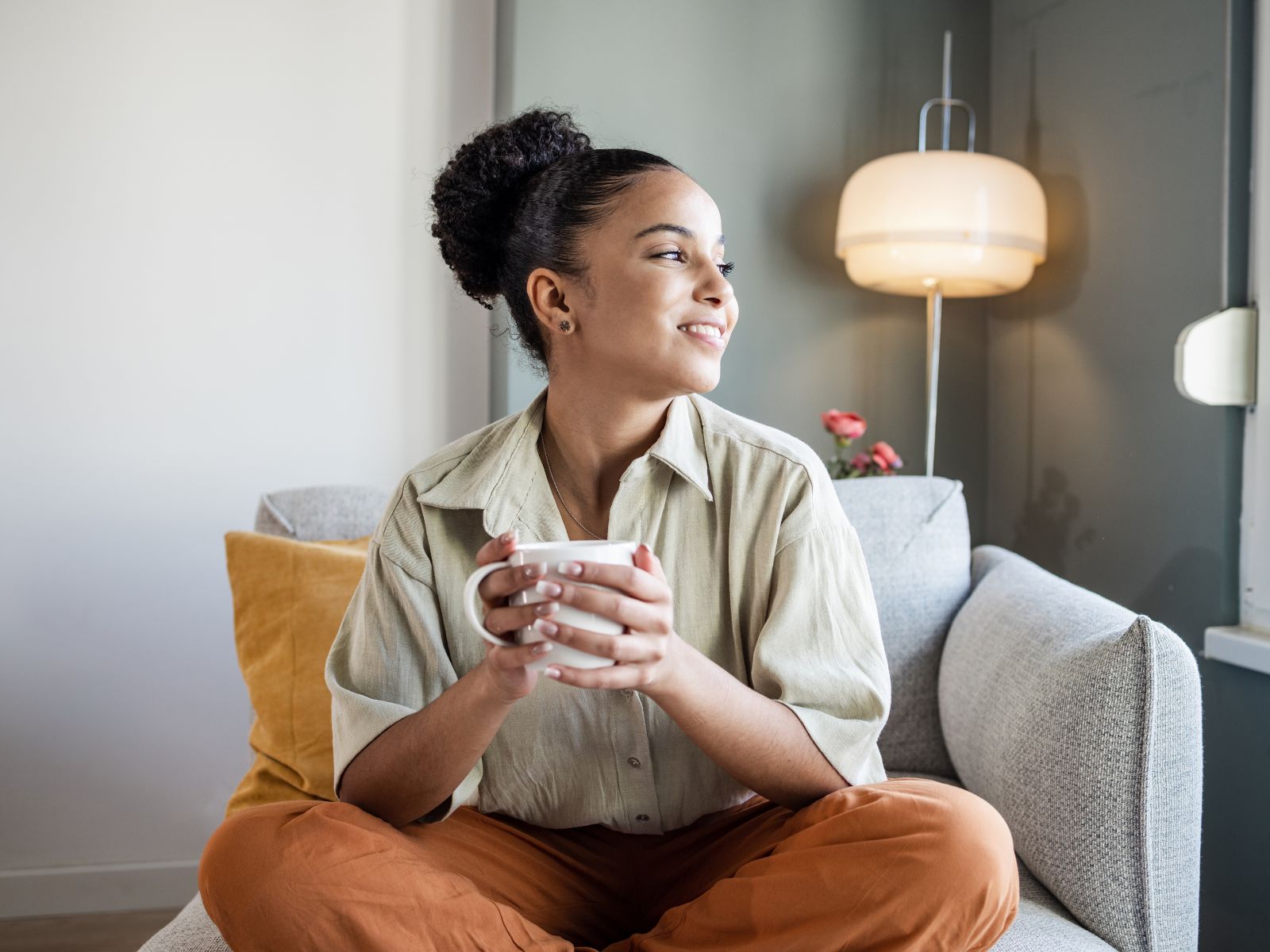 Frau auf einem Sofa mit einem Glas Wasser in der Hand Frau auf einem Sofa mit einem Glas Wasser in der Hand