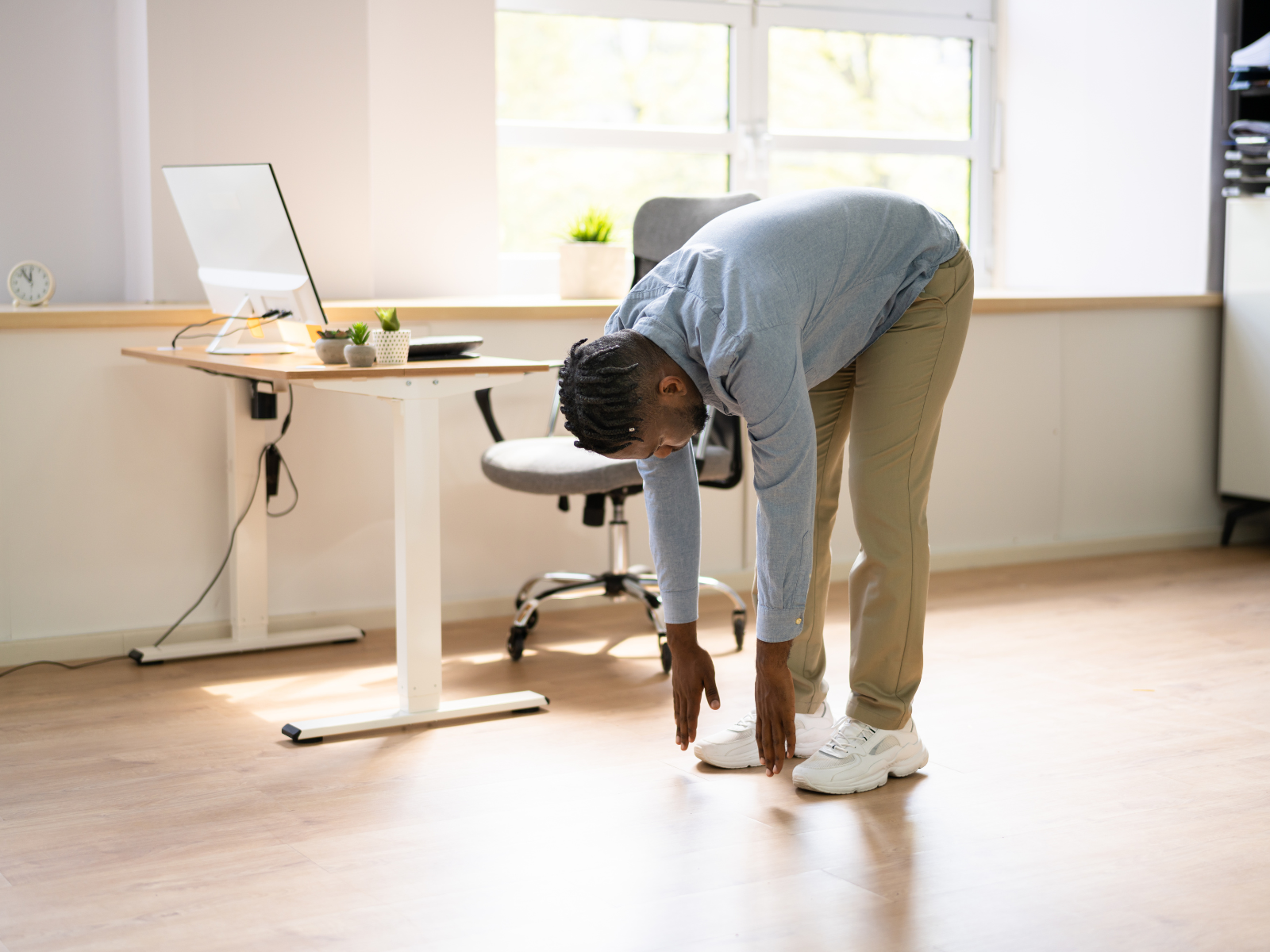 Mann macht Dehnübungen am Schreibtisch