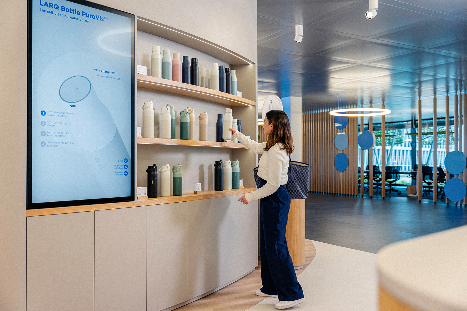 Junge Frau mit LARQ Flasche im BRITA Flagship-Store Eine junge Frau schaut sich LARQ Flaschen im BRITA Flagship-Store an.