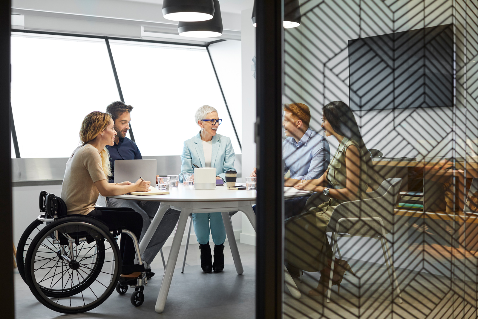 Kolleg:innen sitzen an einem Konferentisch Kolleg:innen, teilweise mit Handicap, sitzen an einem Konferentisch