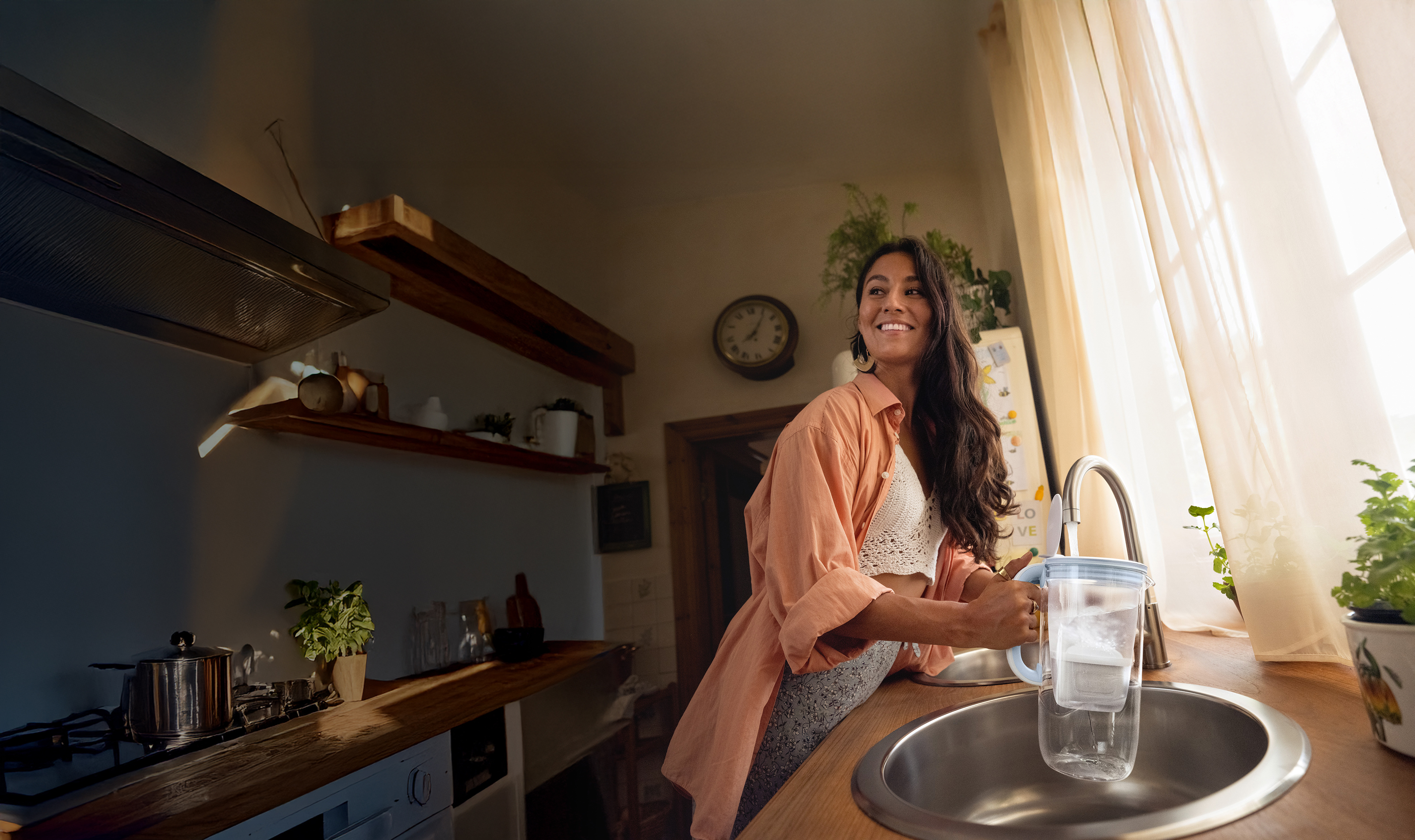 Eine junge Frau filtert Leitungswasser mit dem Tischwasserfilter BRITA Glas
