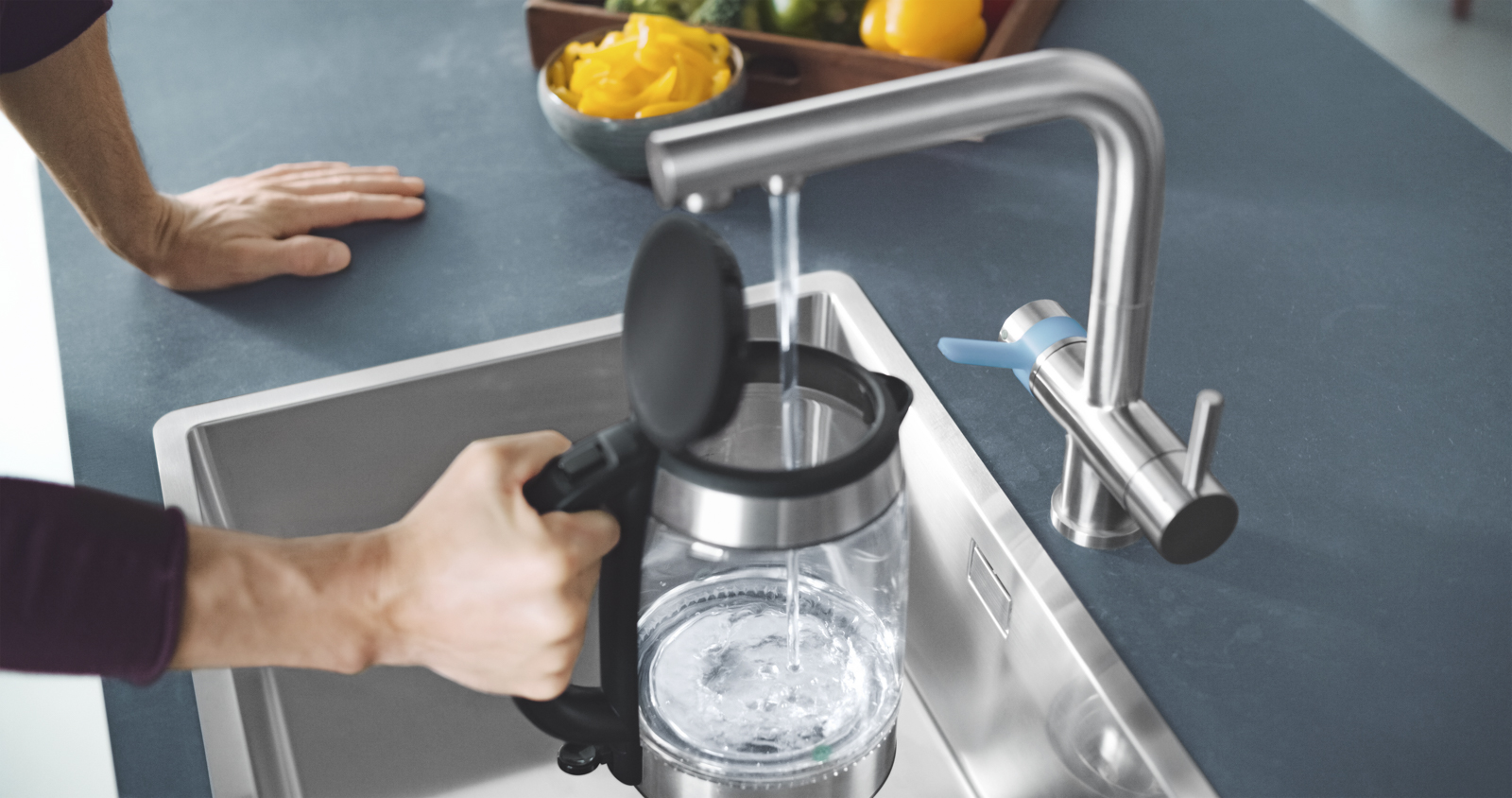 Wasserkocher wird am BRITA 3 Wege Küchenarmatur befüllt Ein Mann füllt in der Küche einen Wasserkocher an einer BRITA 3 Wege Küchenarmatur