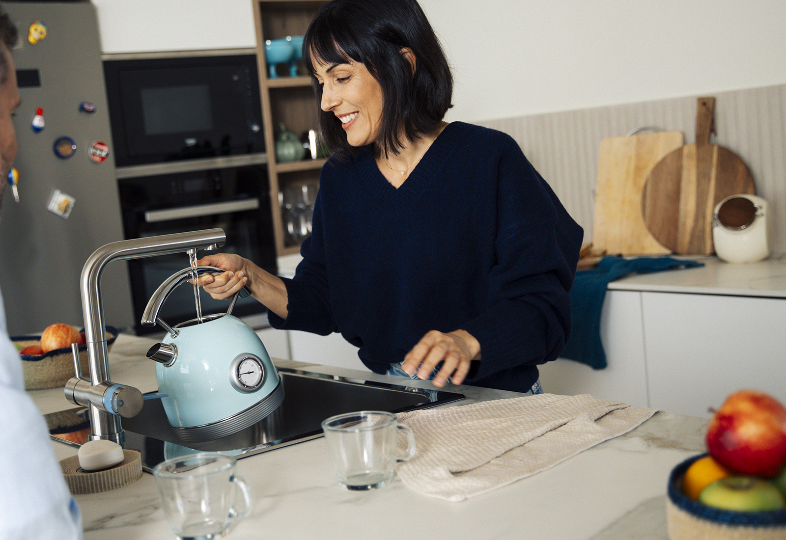 Eine Frau füllt in der Küche einen Wasserkocher an einer BRITA 3 Wege Küchenarmatur
