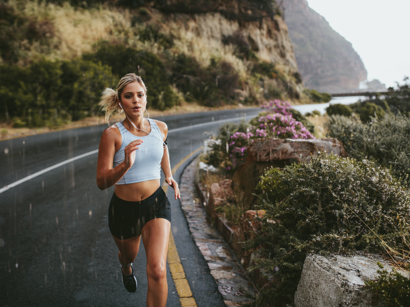 Mindset-Training: Warum so viele mit dem Laufen anfangen Frau joggt an einer Straße im Nieselregen.