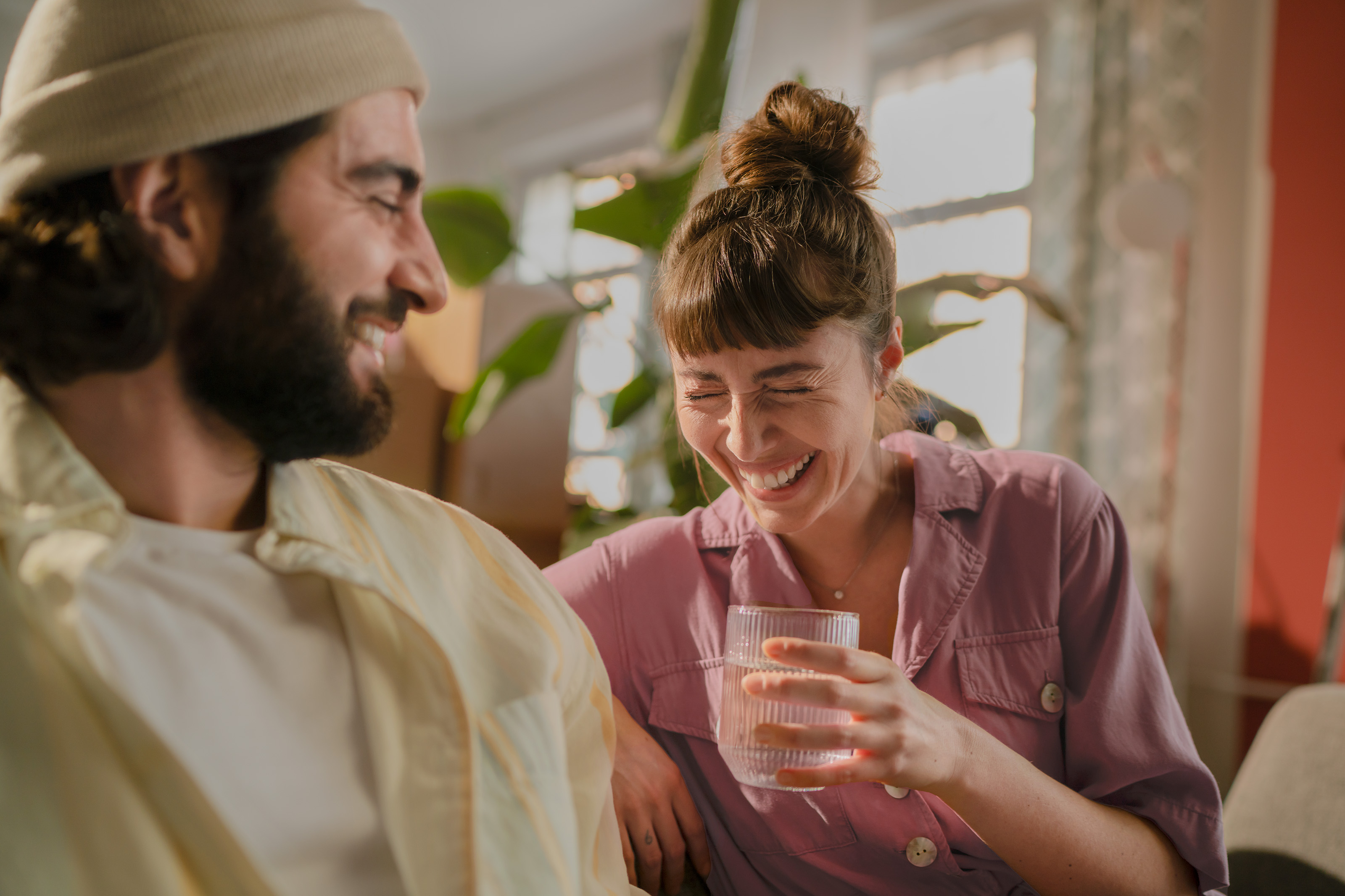 Eine junge Frau trinkt ein Glas Wasser. Eine junge Frau trinkt lachend ein Glas gefiltertes Leitungswasser.