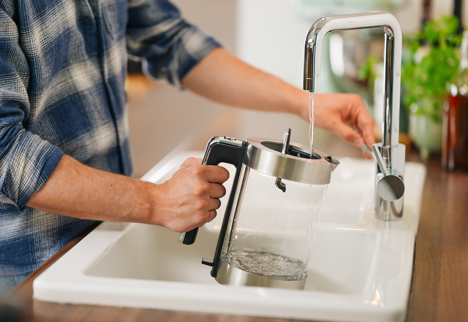 Yource pro select beim Befüllen eines Wasserkochers Person füllt einen Glas-Wasserkocher mit Wasser aus der yource pro select Küchenarmatur