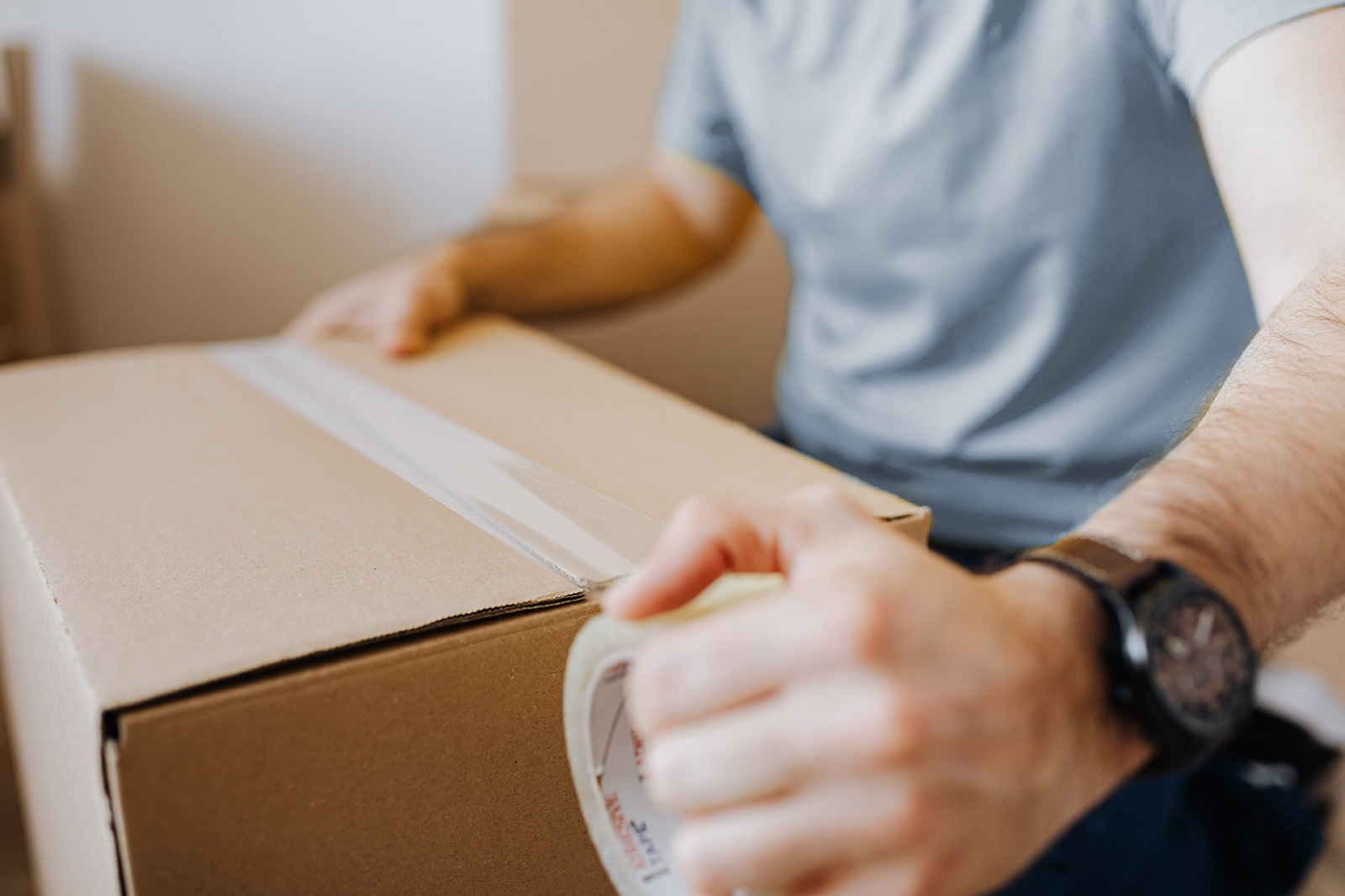 Ein Paket wird mit einem Klebeband verschlossen Ein Paket wird mit einem Klebeband verschlossen