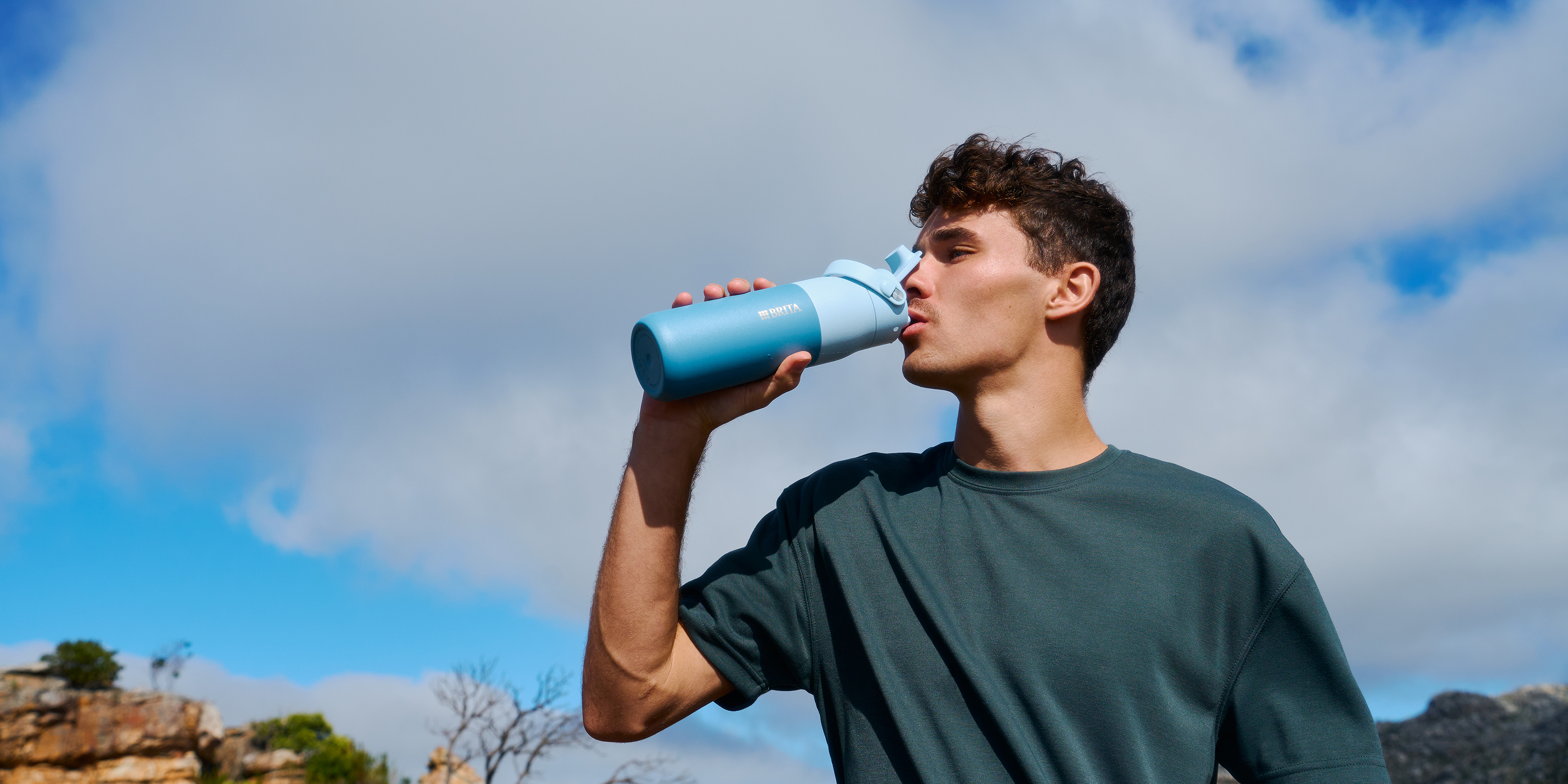 Mann trinkt mit blauer BRITA LARQ Wasserfilterflasche Junger Mann trinkt mit blauer BRITA LARQ Wasserfilterflasche.